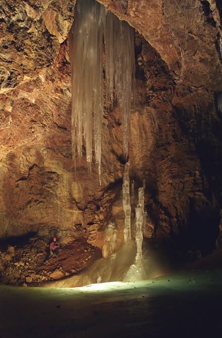 Tall hanging ice formations inside a rocky cave