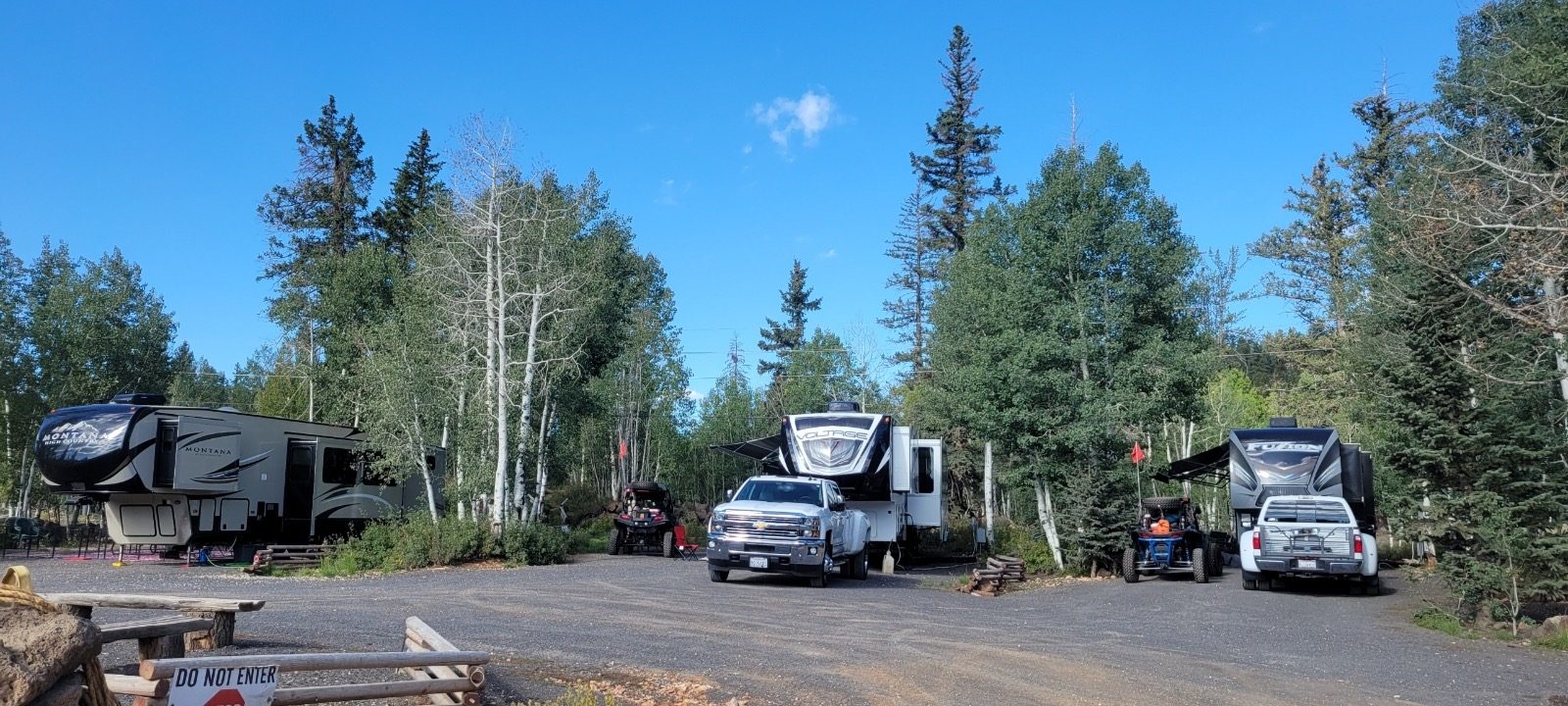 RV trailers and vehicles parked at wooded campsites